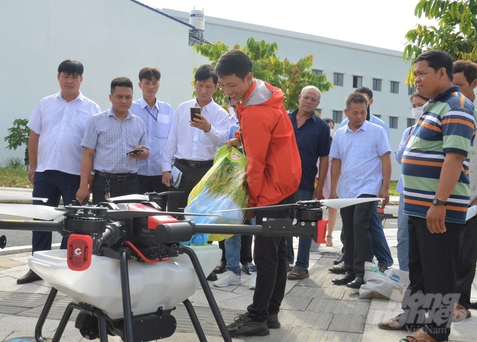 Đoàn xem trình diễn dòng máy bay phục vụ sản xuất nông nghiệp, có thể thực hiện 3 chức năng, sạ lúa, bón phân và phun thuốc BVTV, 1 máy có thể đáp ứng khâu gieo sạ và chăm sóc lúa trên diện tích 250 ha. Ảnh: Trung Chánh.